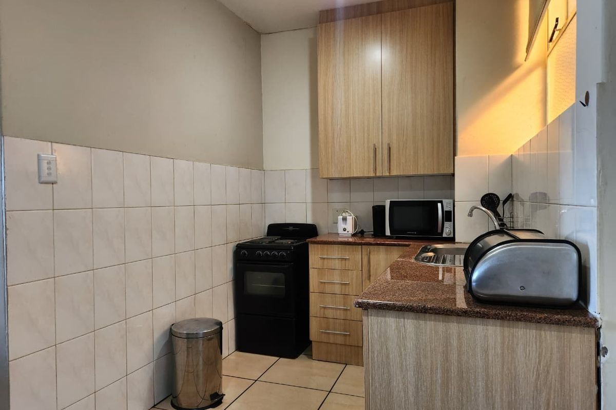 A functional kitchen featuring laminate cabinetry, granite countertops, ceramic wall tiling, and a freestanding oven, offering a practical layout for daily meal preparation.