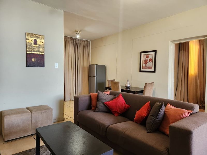 A comfortable living room area featuring tiled flooring and neutral wall tones, providing a functional space for relaxation and dining.
