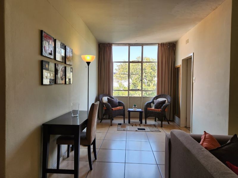 A living area featuring tiled flooring and a large window that provides natural light and an outdoor view.