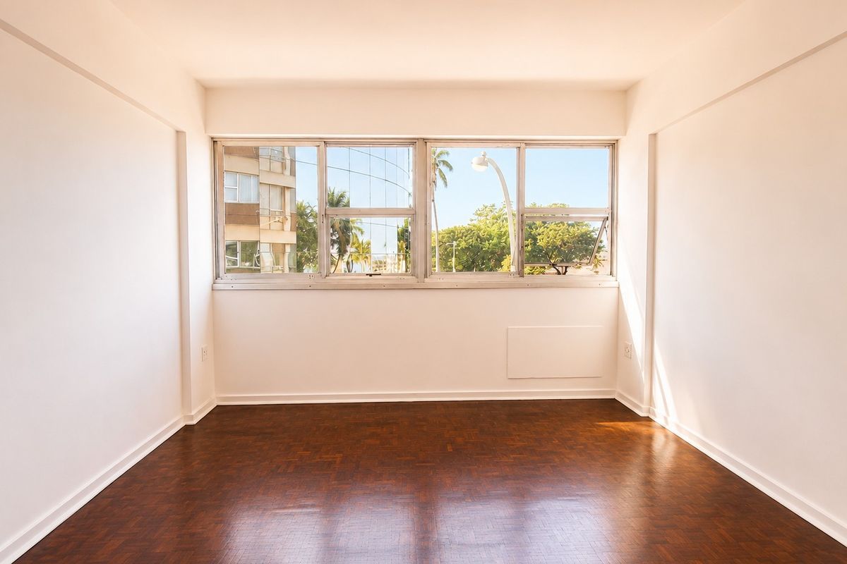 A bright, empty bedroom featuring polished parquet flooring and large windows with natural light, offering a clean canvas for interior design.