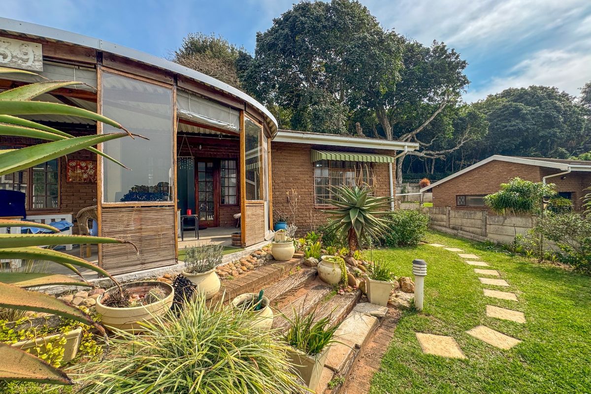 Rear view of the townhouse featuring a curved patio enclosure, brick facade, and a landscaped garden with a stone pathway.