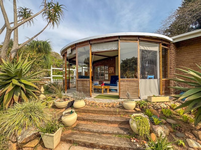 A unique curved patio area featuring timber framing and brickwork, accessible via rustic timber sleeper steps, set within a landscaped garden environment.