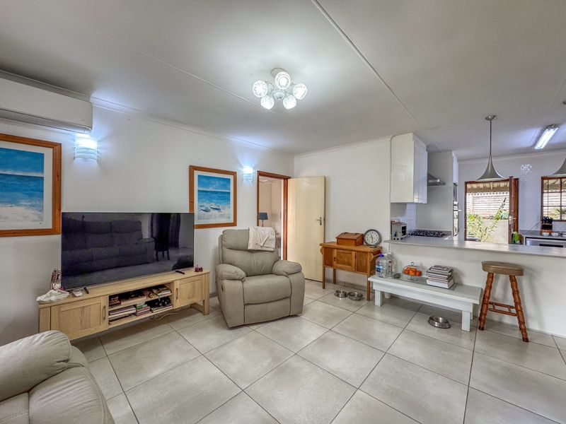 Open-plan living area featuring tiled flooring, a breakfast bar, and integrated kitchen cabinetry, creating a functional and connected space for daily living.