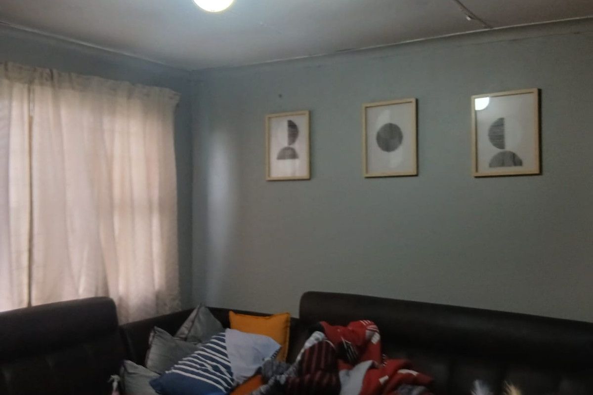 A living room area featuring a ceiling light fixture and curtain rod, showing signs of wear on the ceiling surface.