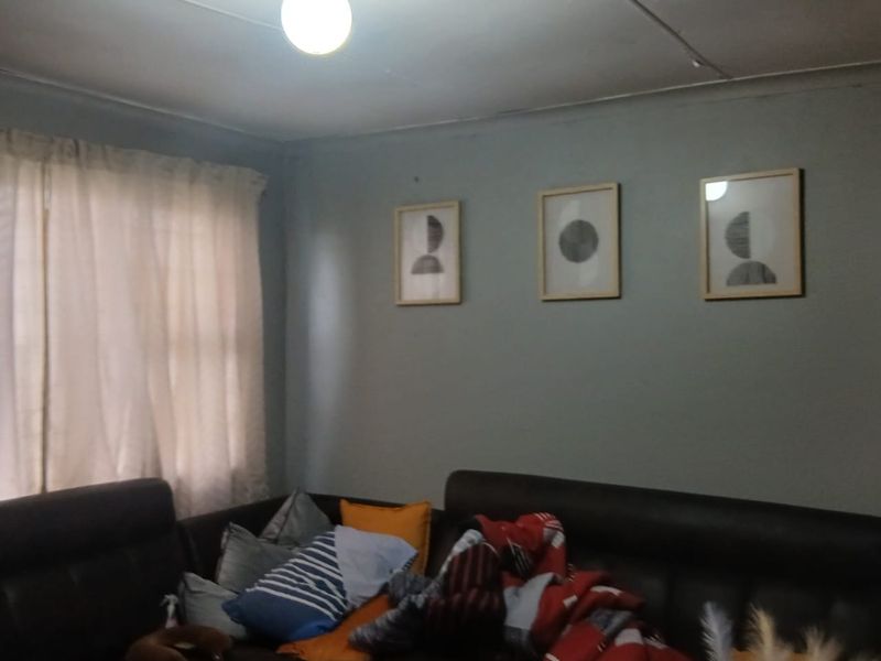 A living room area featuring a ceiling light fixture and curtain rod, showing signs of wear on the ceiling surface.