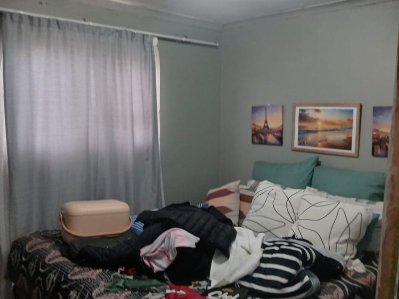 A bedroom featuring neutral wall tones and a window with a curtain rod, requiring minor cosmetic updates to improve the overall finish.