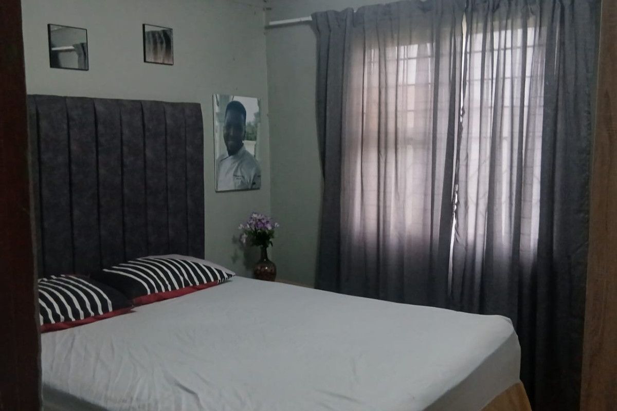 A standard bedroom featuring tiled flooring and window treatments, providing a functional sleeping space.