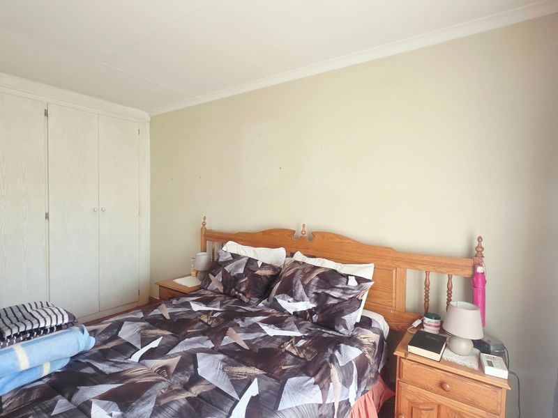 A functional bedroom featuring built-in cupboards and neutral wall finishes, providing a practical space for rest.