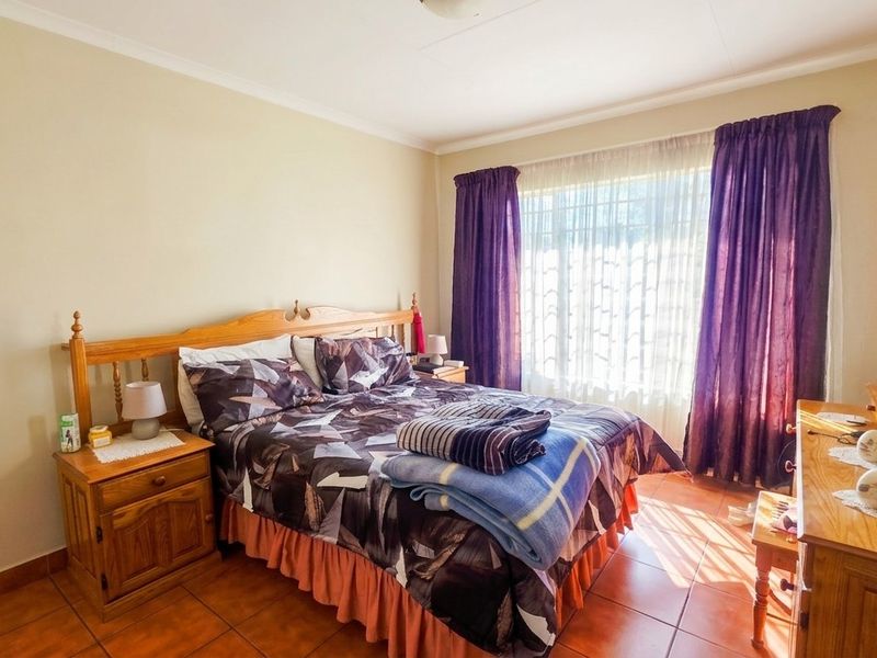 A well-lit bedroom featuring tiled flooring and large windows with curtain rails, offering a functional and comfortable living space.
