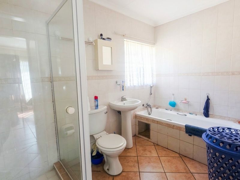 A functional bathroom featuring a shower enclosure, pedestal basin, toilet, and a built-in bathtub with tiled finishes.