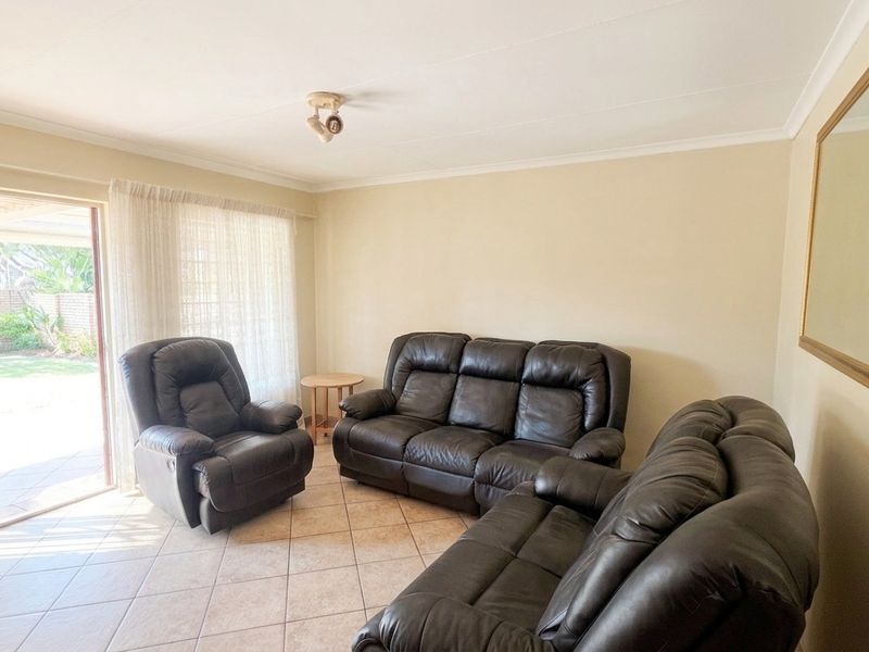 A bright living room featuring ceramic floor tiles and a sliding glass door providing direct access to the outdoor patio area.