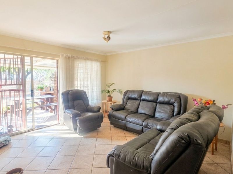 Spacious living room featuring neutral tiled flooring and a large sliding glass door providing direct access to the outdoor patio area.