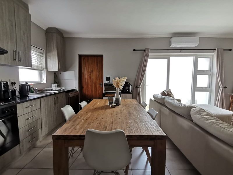 Open-plan kitchen and living area featuring modern cabinetry, integrated appliances, tiled flooring, and sliding door access to the exterior.