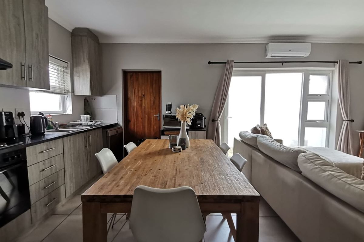 Open-plan kitchen and living area featuring modern cabinetry, integrated appliances, tiled flooring, and sliding door access to the exterior.