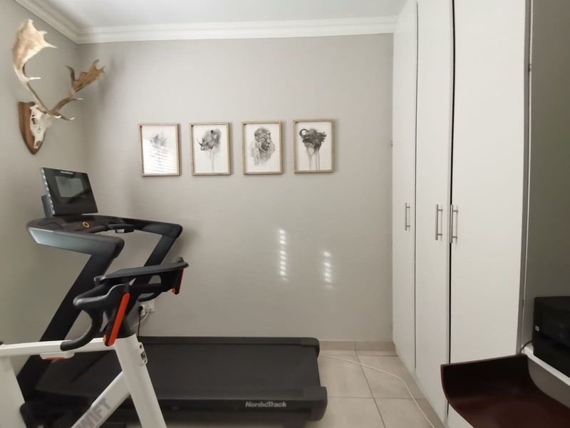 A bedroom featuring neutral wall tones, tiled flooring, and ample built-in cupboard storage space.