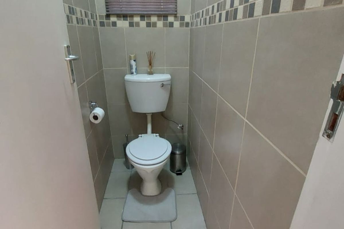 A compact guest bathroom featuring neutral ceramic wall and floor tiles with a decorative mosaic border.
