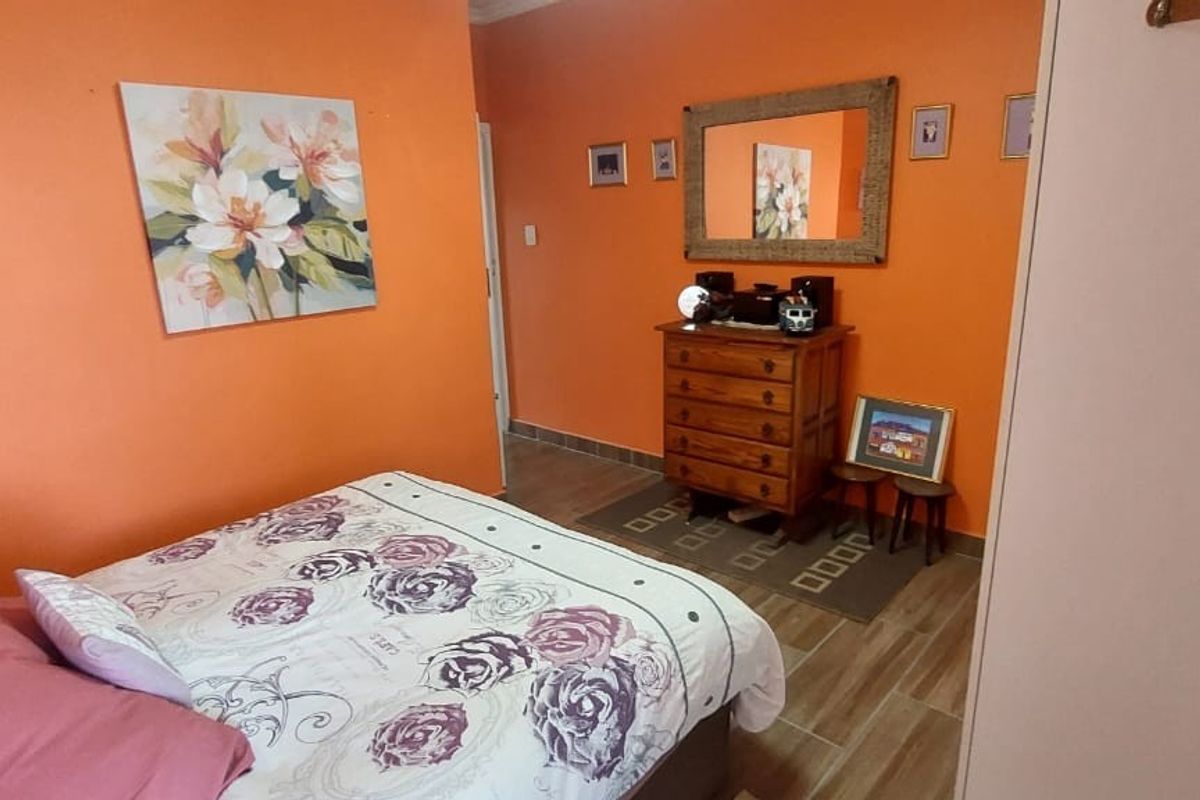 A bedroom featuring tiled flooring and a built-in wardrobe, currently finished with vibrant orange wall paint.