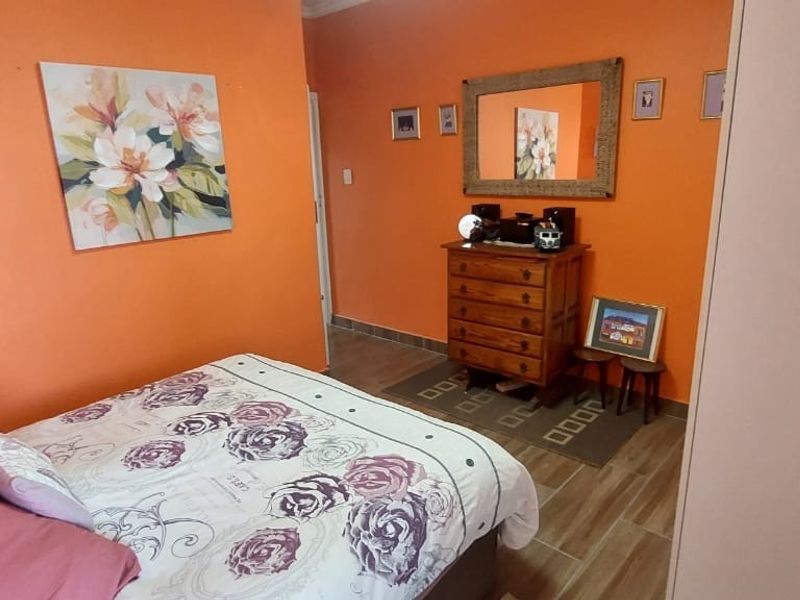 A bedroom featuring tiled flooring and a built-in wardrobe, currently finished with vibrant orange wall paint.