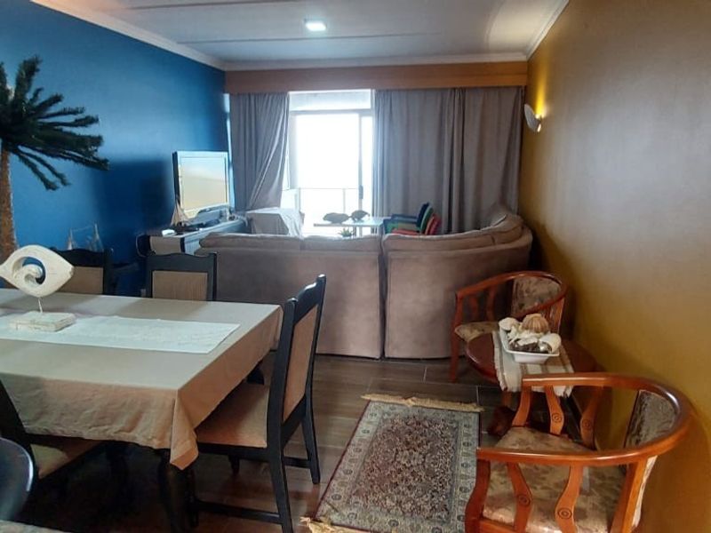 Open plan living and dining area featuring tiled flooring and direct access to a balcony through sliding glass doors.