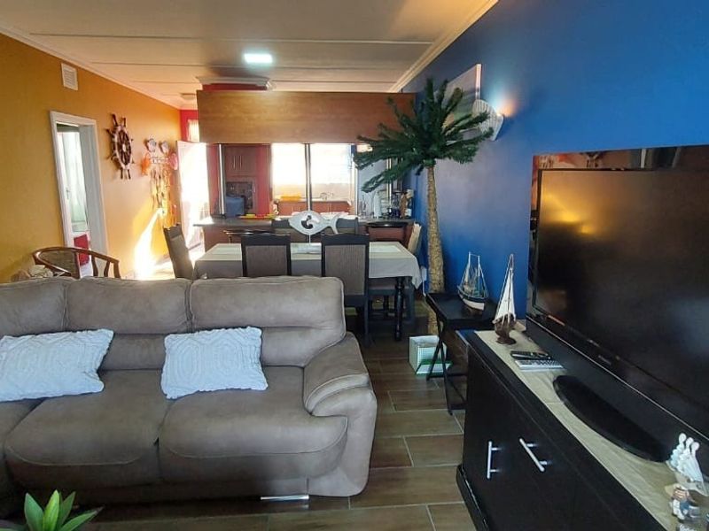 Open plan living and dining area featuring tiled flooring and a connected kitchen space with a central island.