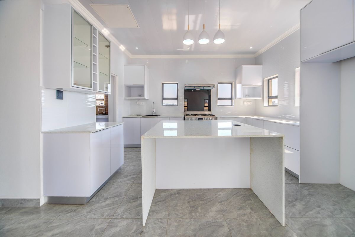 Modern, bright kitchen featuring a central island, sleek white cabinetry, quartz countertops, and high-quality built-in appliances.
