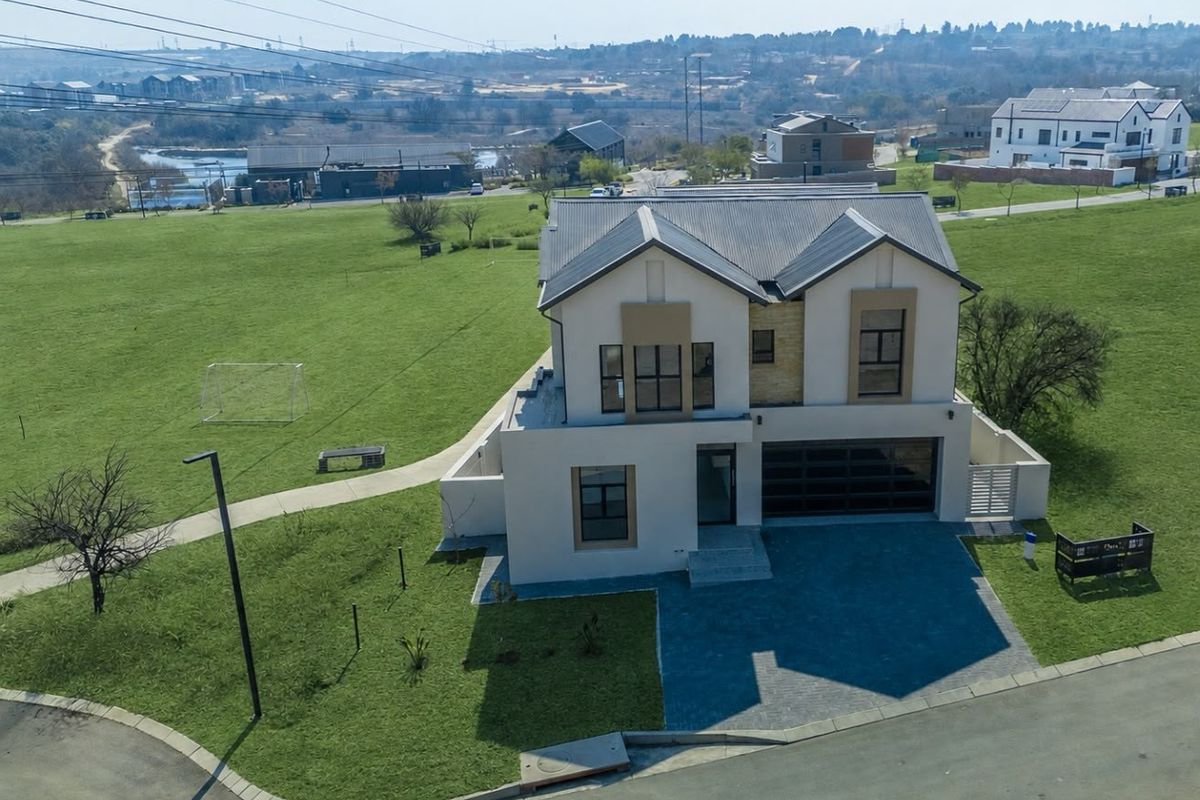 Aerial view of a modern two-story residential home featuring a paved driveway, double garage, and contemporary architectural design set in a spacious estate.