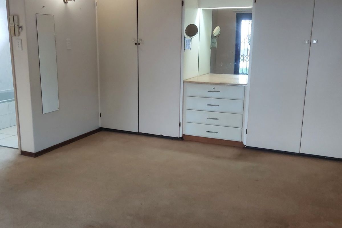 Spacious bedroom featuring extensive built-in cupboards, a integrated vanity unit, and direct access to an en-suite bathroom.