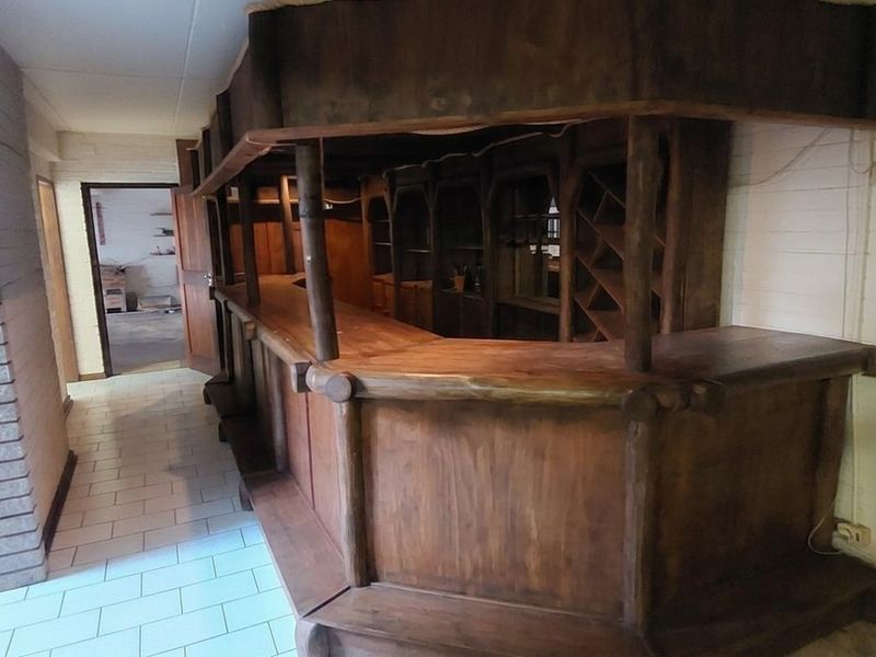 A dedicated bar area featuring a large built-in wooden counter, brick archway detail, and tiled flooring, offering potential for a modern entertainment space.