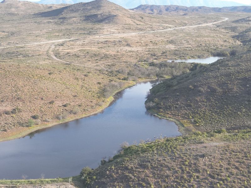 An elevated aerial view of a natural dam and surrounding rural landscape on the farm property.