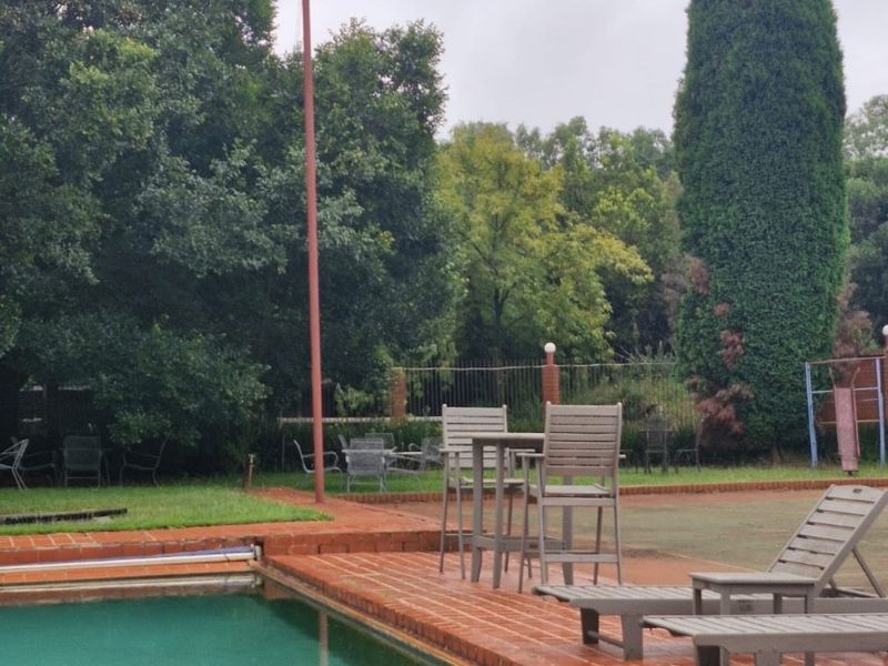 Outdoor pool area featuring a brick-paved deck and swimming pool, set within a spacious garden environment.