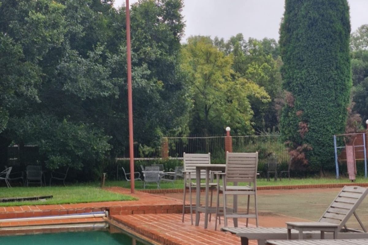 Outdoor pool area featuring a brick-paved deck and swimming pool, set within a spacious garden environment.