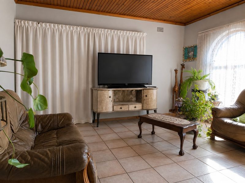 A living room featuring ceramic floor tiles, a timber-paneled ceiling, and an arched window, providing a functional and traditional living space.