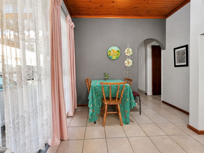 Dining area featuring ceramic floor tiles, a warm timber tongue and groove ceiling, and a classic arched doorway leading to the hallway.