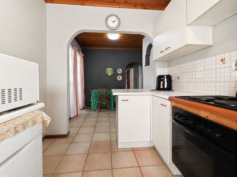 A functional kitchen featuring built-in cabinetry, a tiled backsplash, and an integrated oven, leading through an archway into an adjacent dining area.