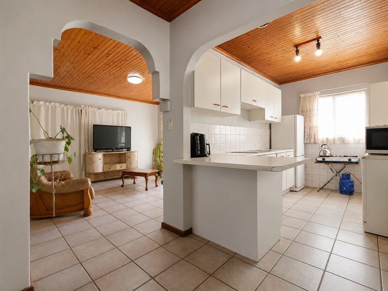 Open plan living and kitchen area featuring timber ceilings, tiled flooring, and a breakfast bar, creating a functional and connected living space.