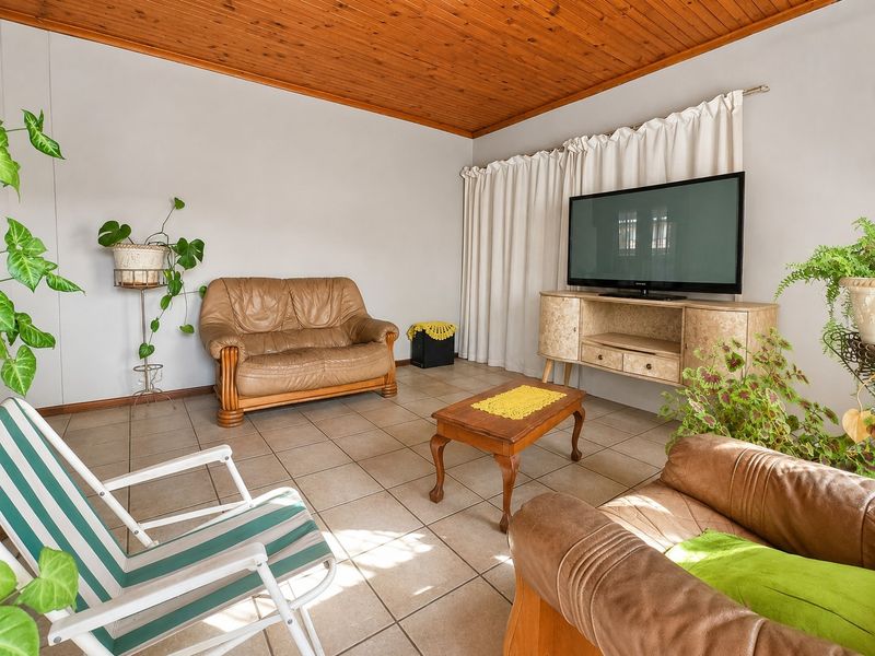 A living room featuring tiled flooring and a timber tongue and groove ceiling.