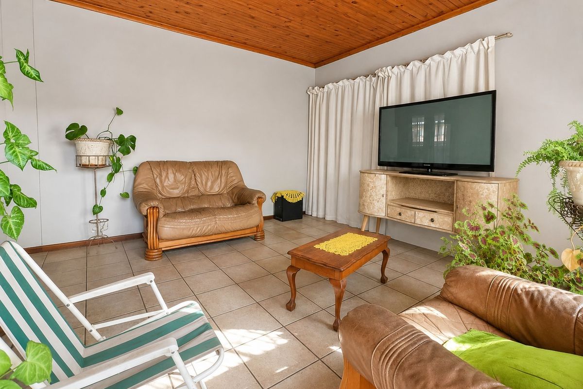A living room featuring tiled flooring and a timber tongue and groove ceiling.