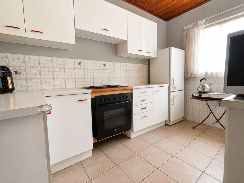 A functional kitchen featuring white built-in cabinetry, a tiled backsplash, a built-in oven with hob, and tiled flooring under a timber ceiling.