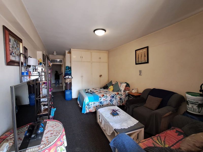 A bedroom featuring built-in cupboards and carpeted flooring, offering a functional layout with potential for cosmetic updates to enhance the living space.