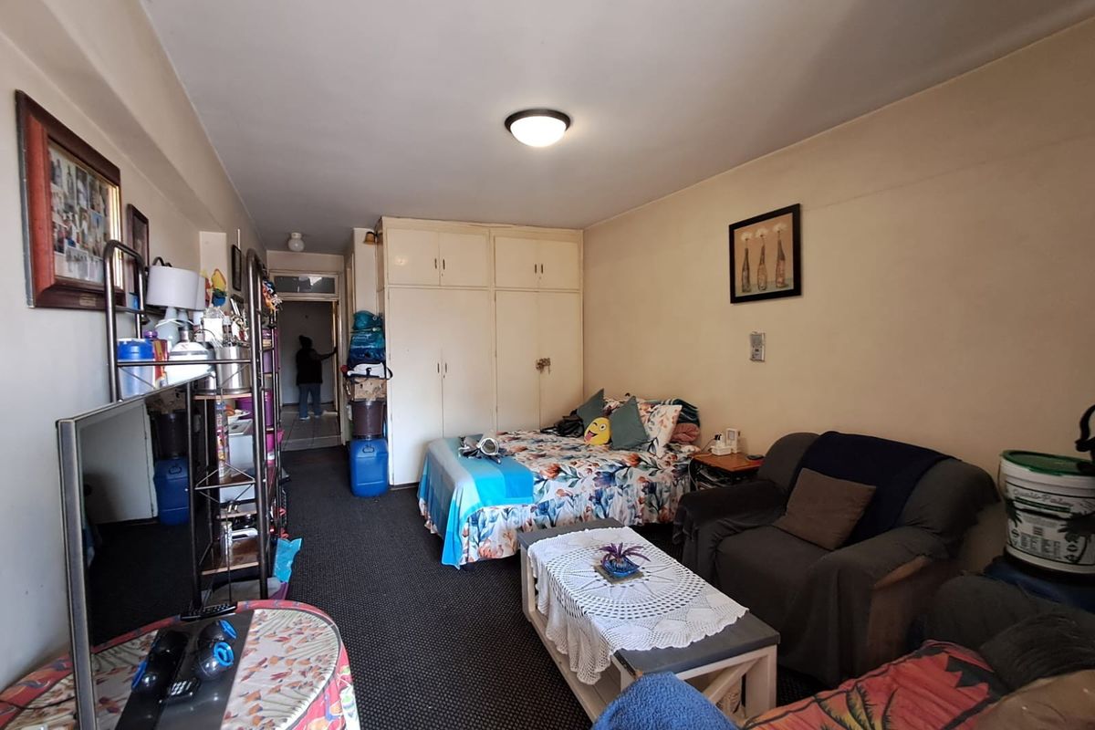 A bedroom featuring built-in cupboards and carpeted flooring, offering a functional layout with potential for cosmetic updates to enhance the living space.