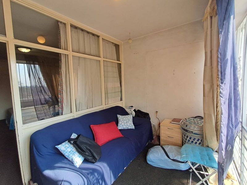 An enclosed balcony area featuring large glass partitions and fixed window frames, offering a versatile space that could be updated for modern living.