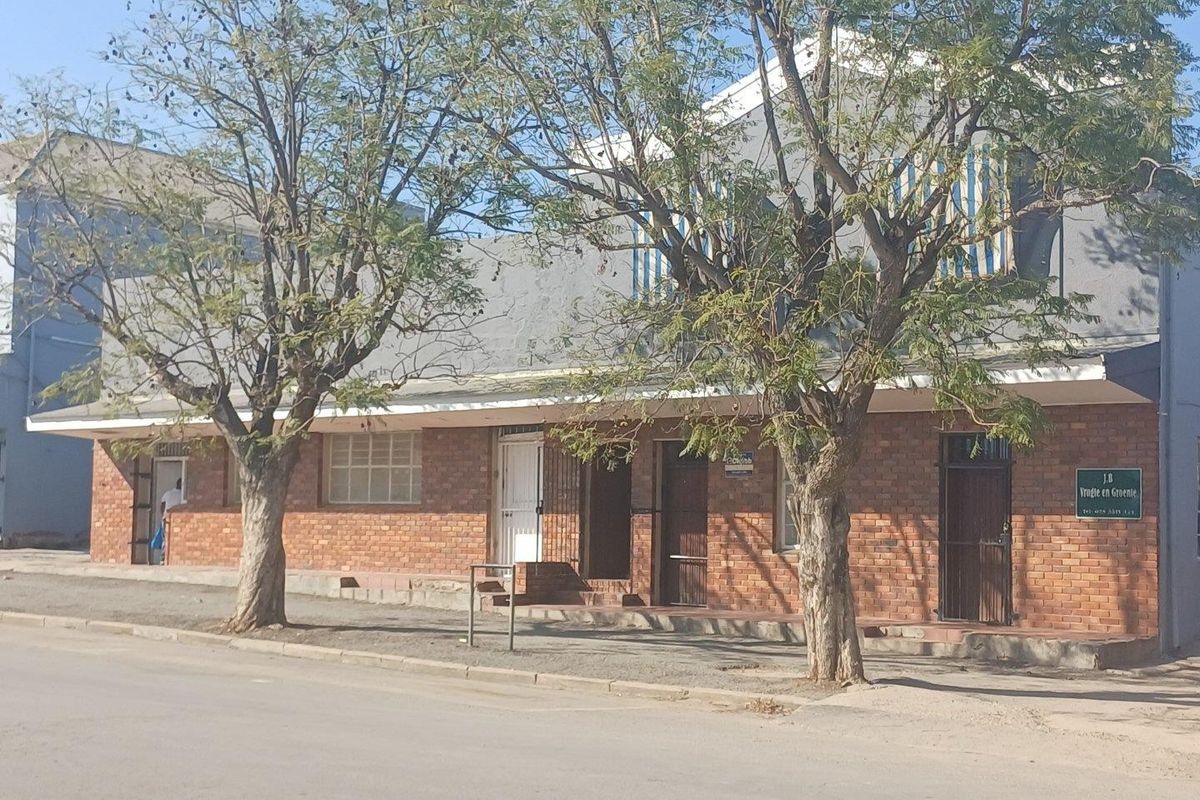 Front exterior view of a commercial brick building featuring multiple entrances, security gates, and street-level access.