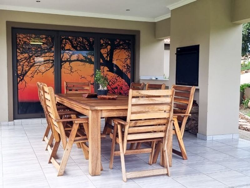 Covered outdoor patio featuring tiled flooring, recessed lighting, and a built-in braai, providing a functional space for outdoor dining and entertainment.