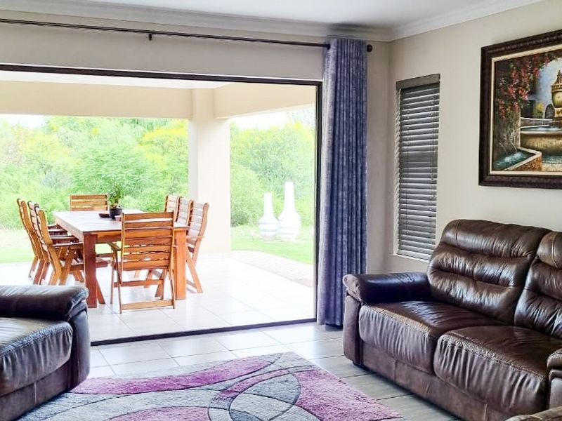 Spacious living room featuring large sliding glass doors that open onto a covered patio, providing seamless indoor-outdoor flow and natural light.