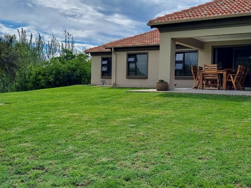 Rear view of the house featuring a covered patio, sliding glass doors, and a well-maintained lawn area.