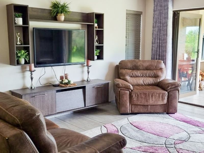 A comfortable living room featuring a built-in media unit, tiled flooring, and large sliding glass doors that provide seamless access to the outdoor patio area.