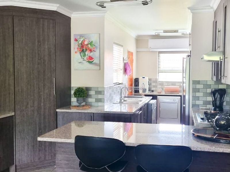 Modern kitchen featuring dark wood cabinetry, granite countertops, tiled backsplash, and a gas hob with an integrated extractor fan.