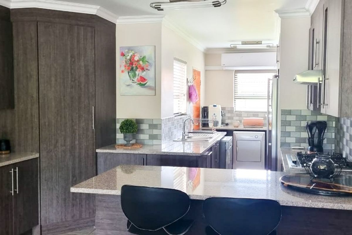 Modern kitchen featuring dark wood cabinetry, granite countertops, tiled backsplash, and a gas hob with an integrated extractor fan.