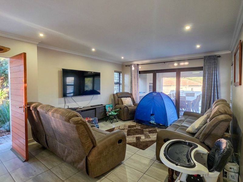 Spacious living room featuring tiled flooring, recessed downlights, and large sliding glass doors providing direct access to the outdoor patio area.