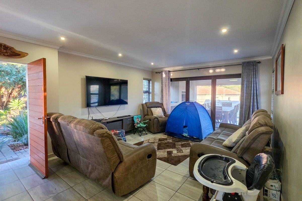 Spacious living room featuring tiled flooring, recessed downlights, and large sliding glass doors providing direct access to the outdoor patio area.
